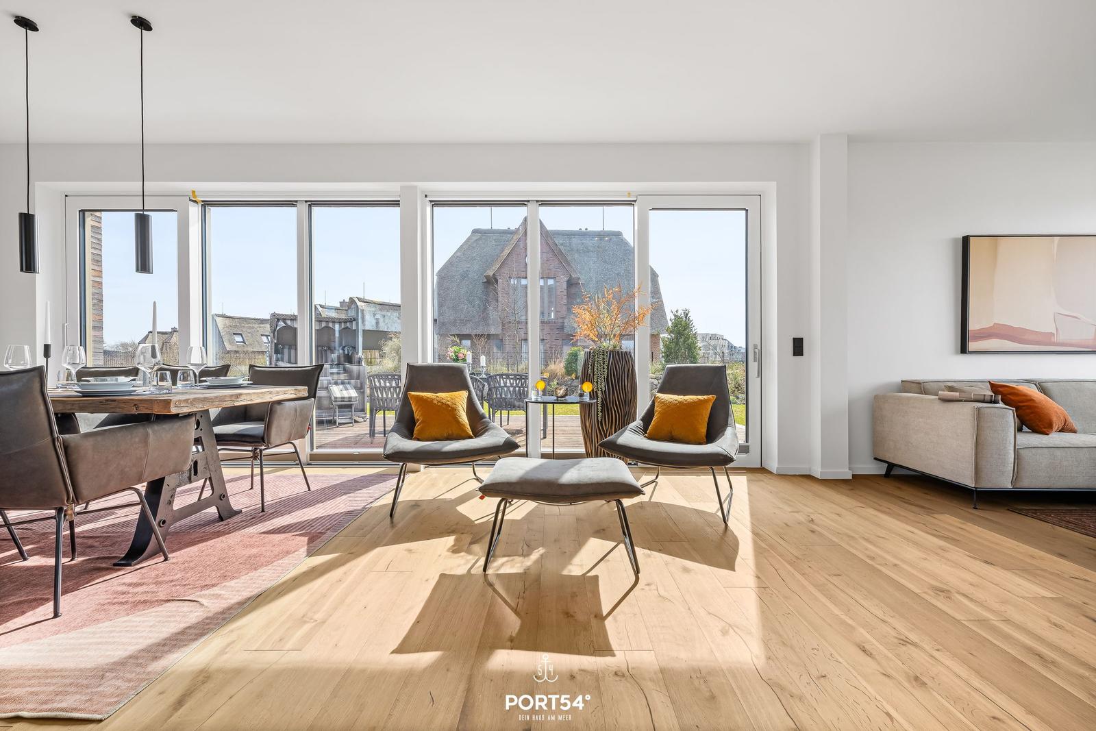Living and dining area with wooden floor, seating, and view of the garden.