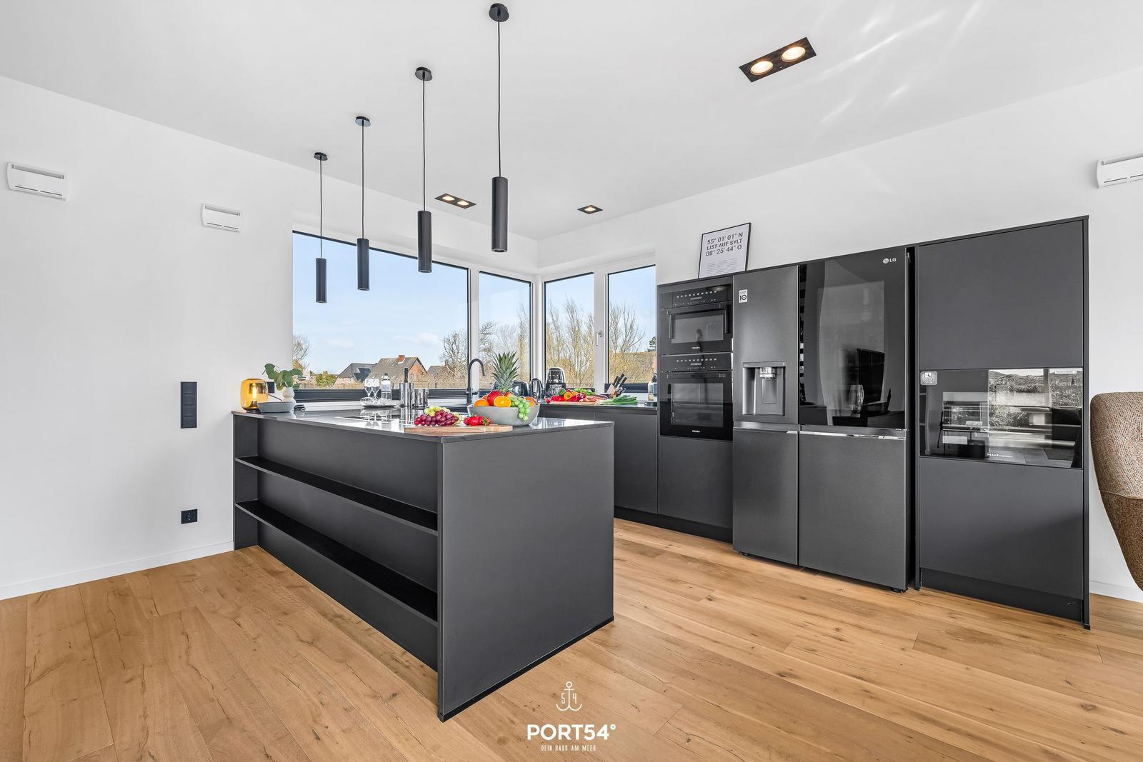 Modern kitchen with dark cabinets, kitchen island, and large windows.