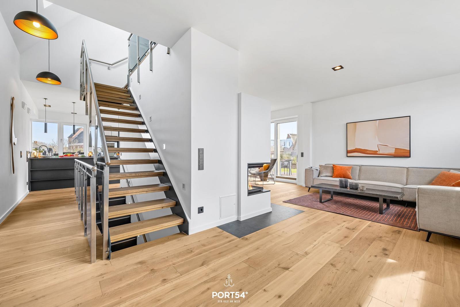 Apartment with wooden floors, staircase, and modern living area with sofa and fireplace.