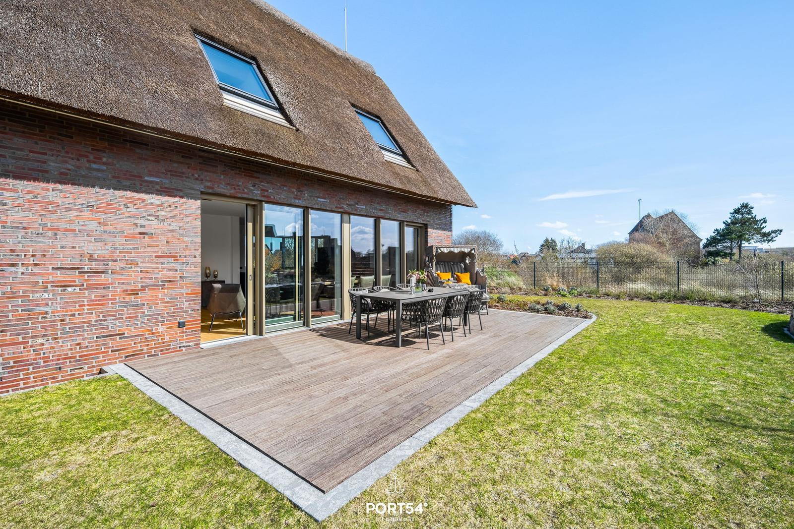 House with roof terrace, dining area, and garden. Wooden terrace and seating group.
