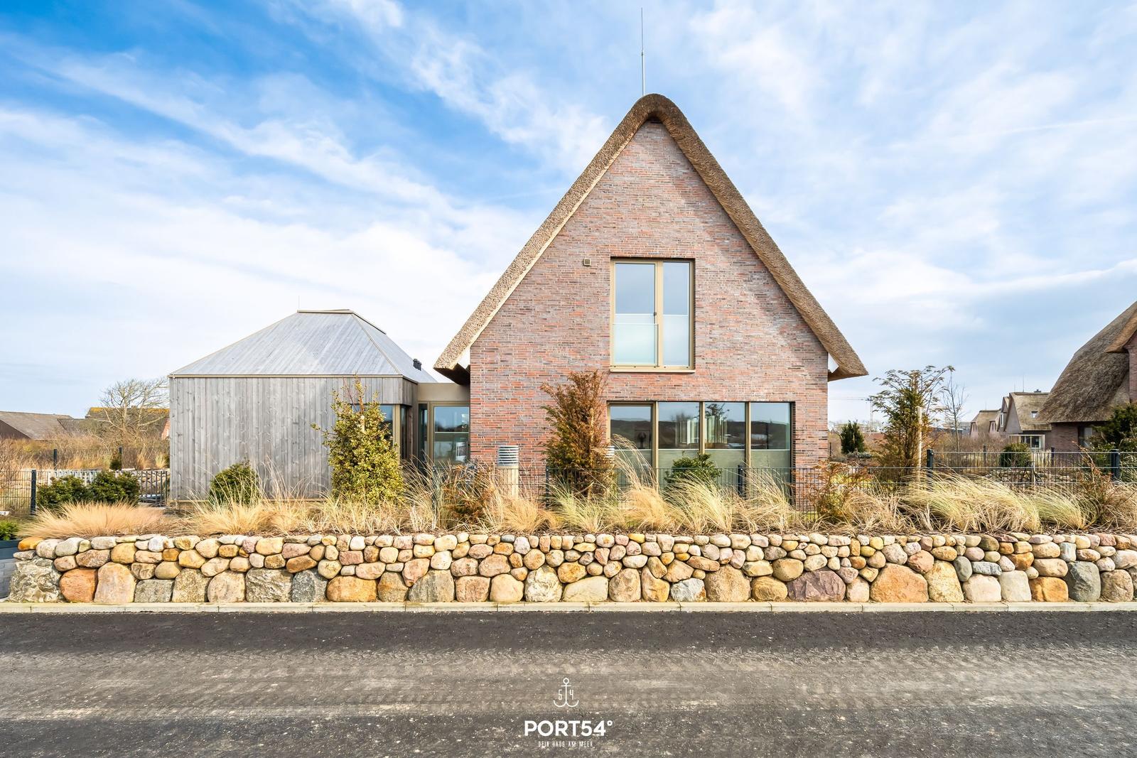 Modern villa with thatched roof and stone wall