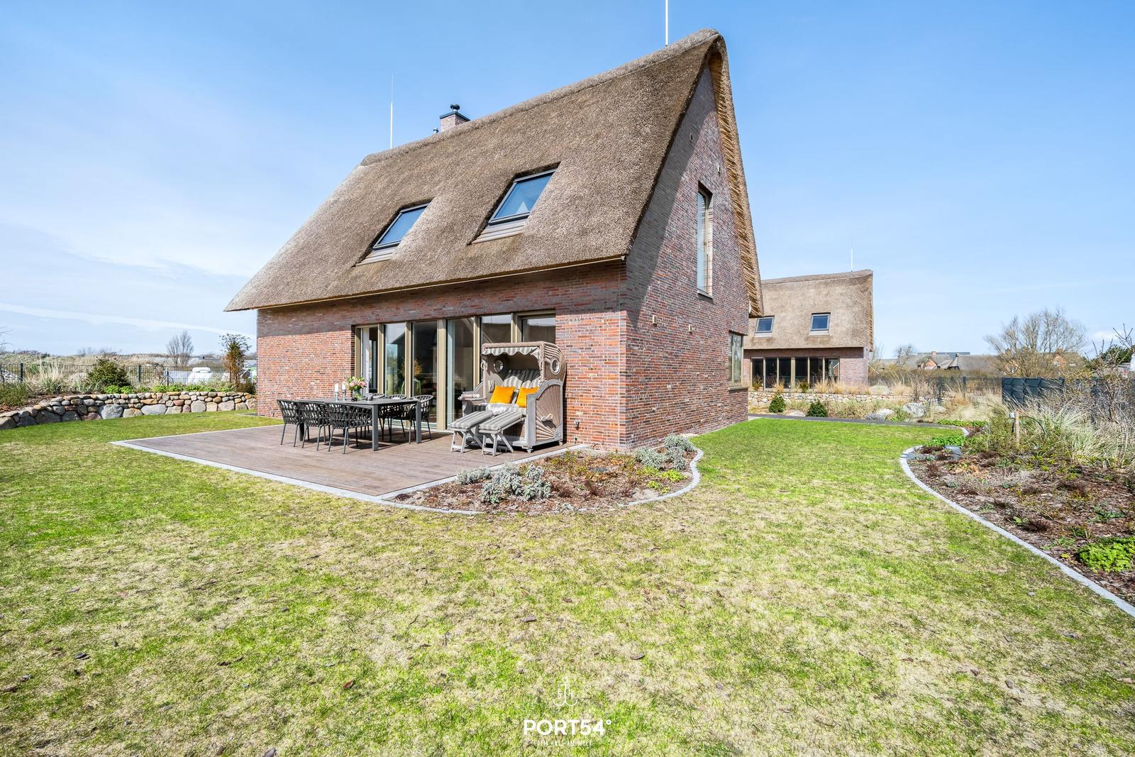 House with thatched roof and terrace with garden