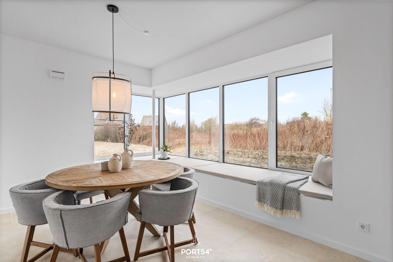 Dining room with round table, gray chairs, and large window view.