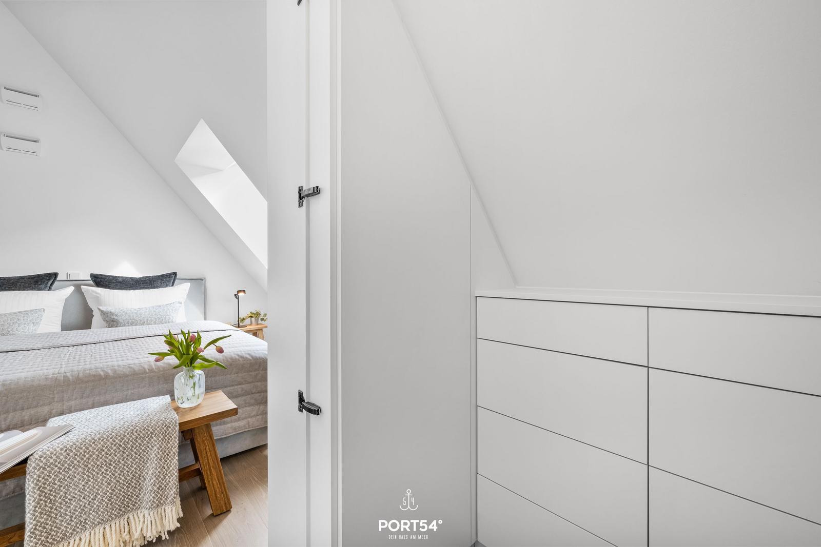 Bedroom with sloped ceiling, bed, nightstand, and wardrobe