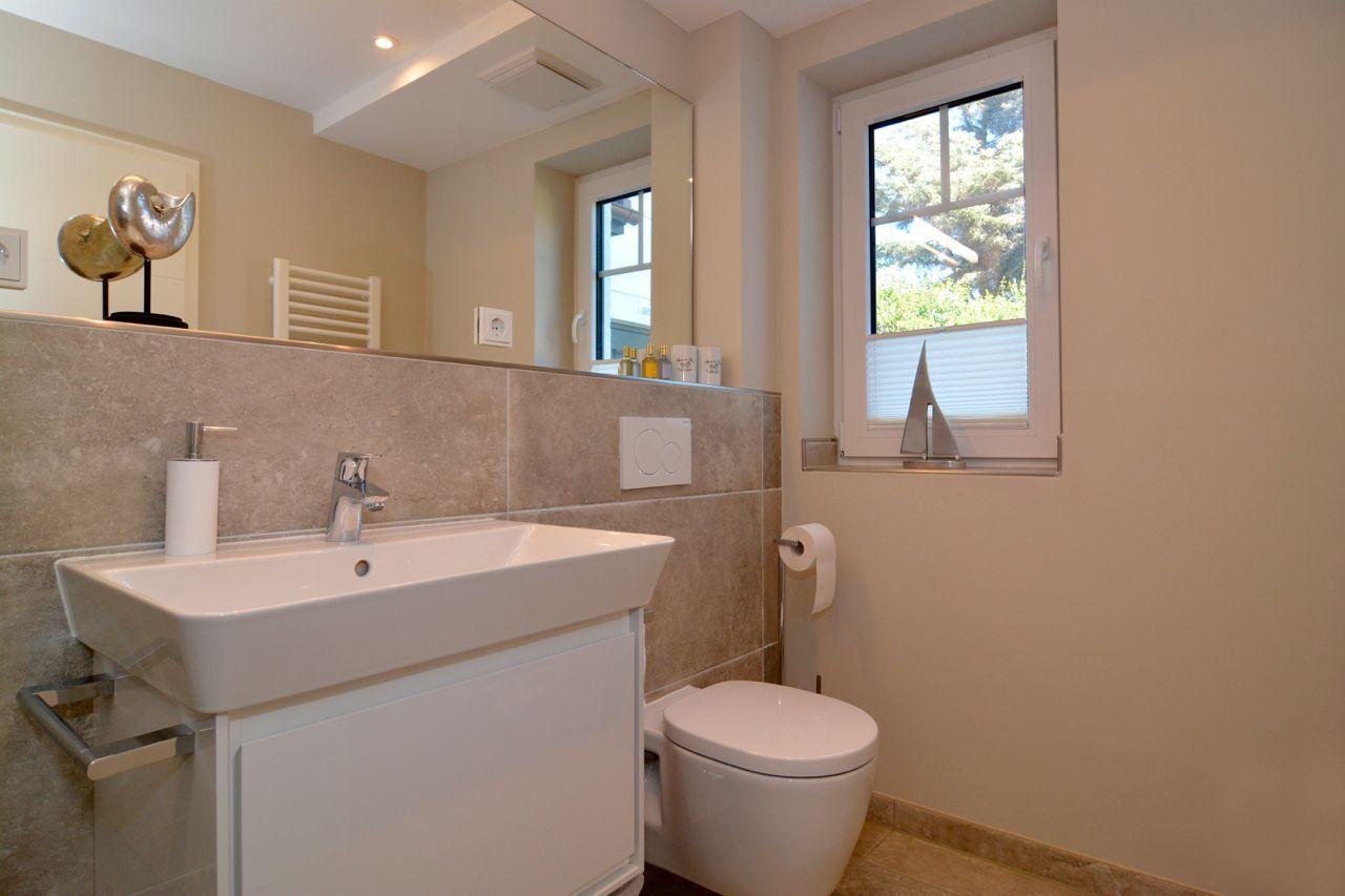 Bathroom with sink, toilet, and window with view outside.