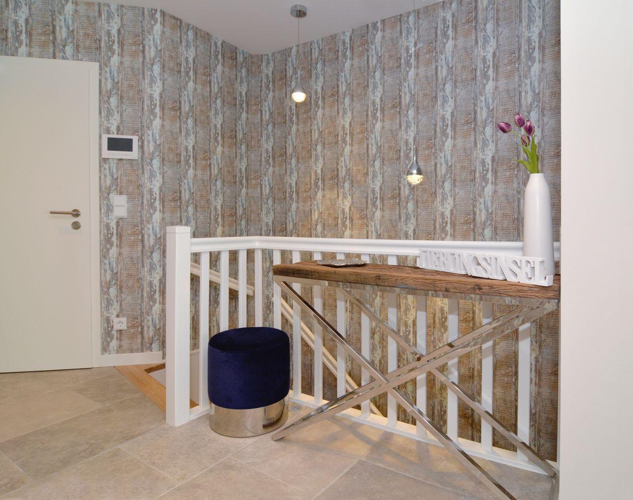 Entrance area with wooden bench, blue ottoman, and wood-patterned wallpaper.