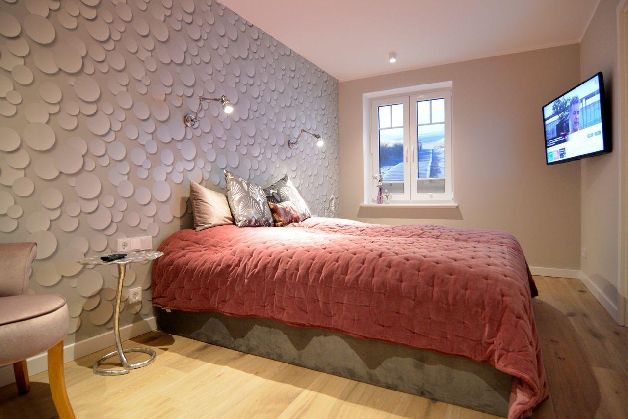 Bedroom with bed, window, and wall with round decorative elements.