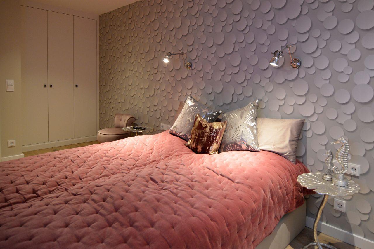 Bedroom with patterned wall, bed with pillows, and nightstand with seahorse decoration.