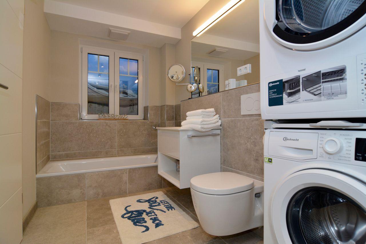 Bathroom with bathtub, toilet, and washing machine.