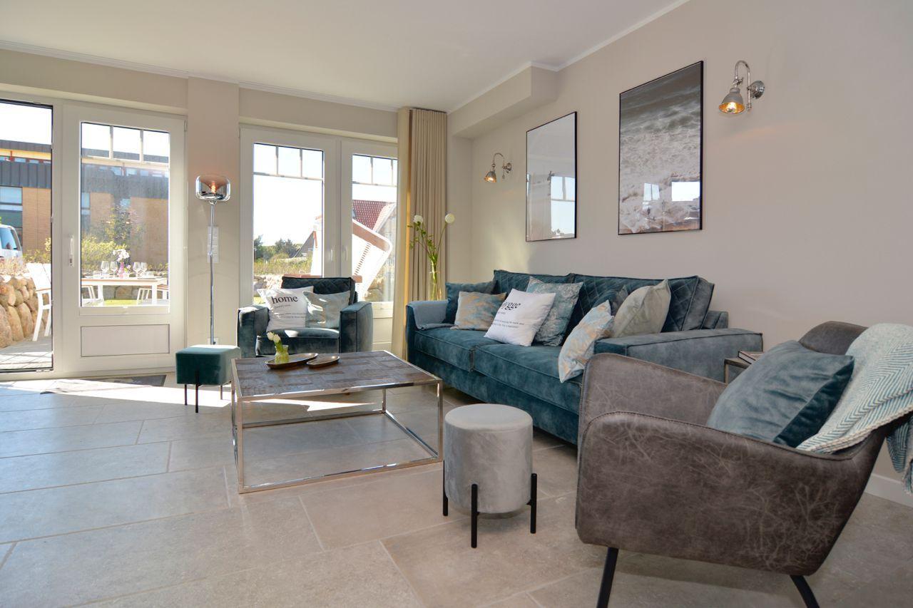 Living room with sofa, armchairs, and table. Doorways to outdoor area.