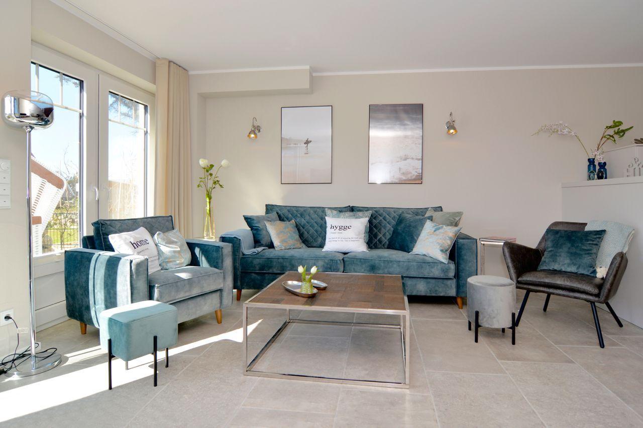 Living room with blue sofa, seating, and windows with view.