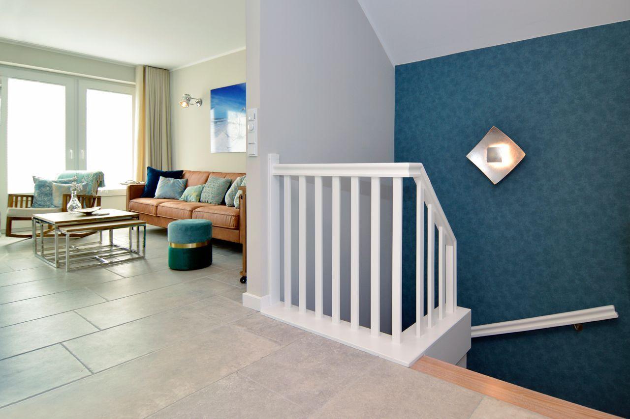Living area with sofa, table, and staircase with blue wall.