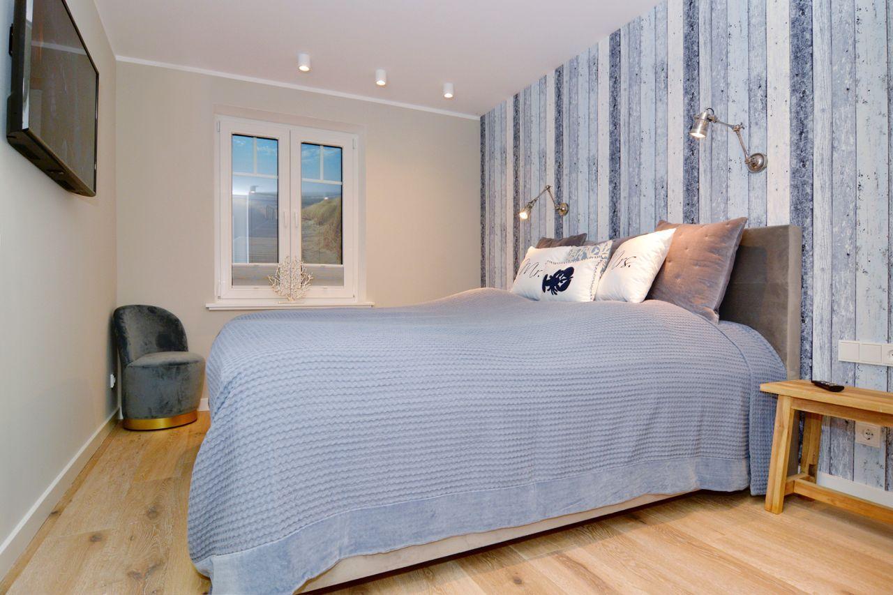 Bedroom with bed, window, and wall lighting.