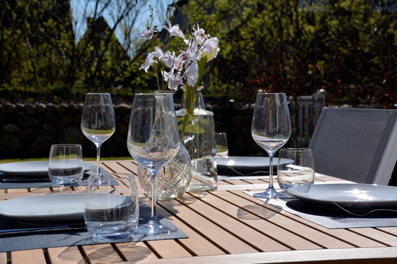 Set table with glasses and flowers in the garden