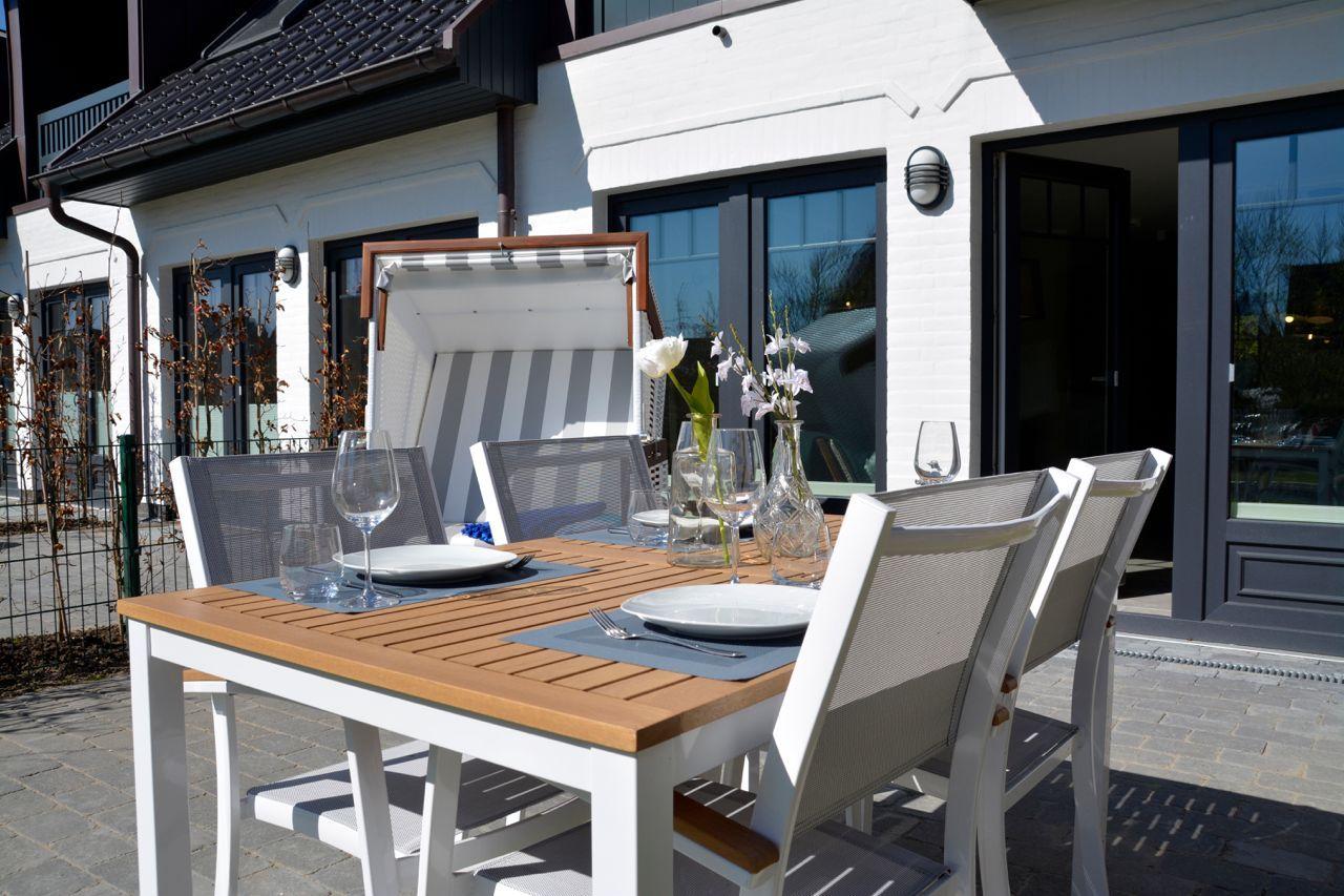Terrace with table, chairs, and sunshade in front of white house