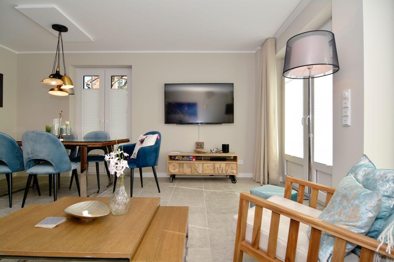 Living and dining area with TV, sofa, and dining table with blue chairs.
