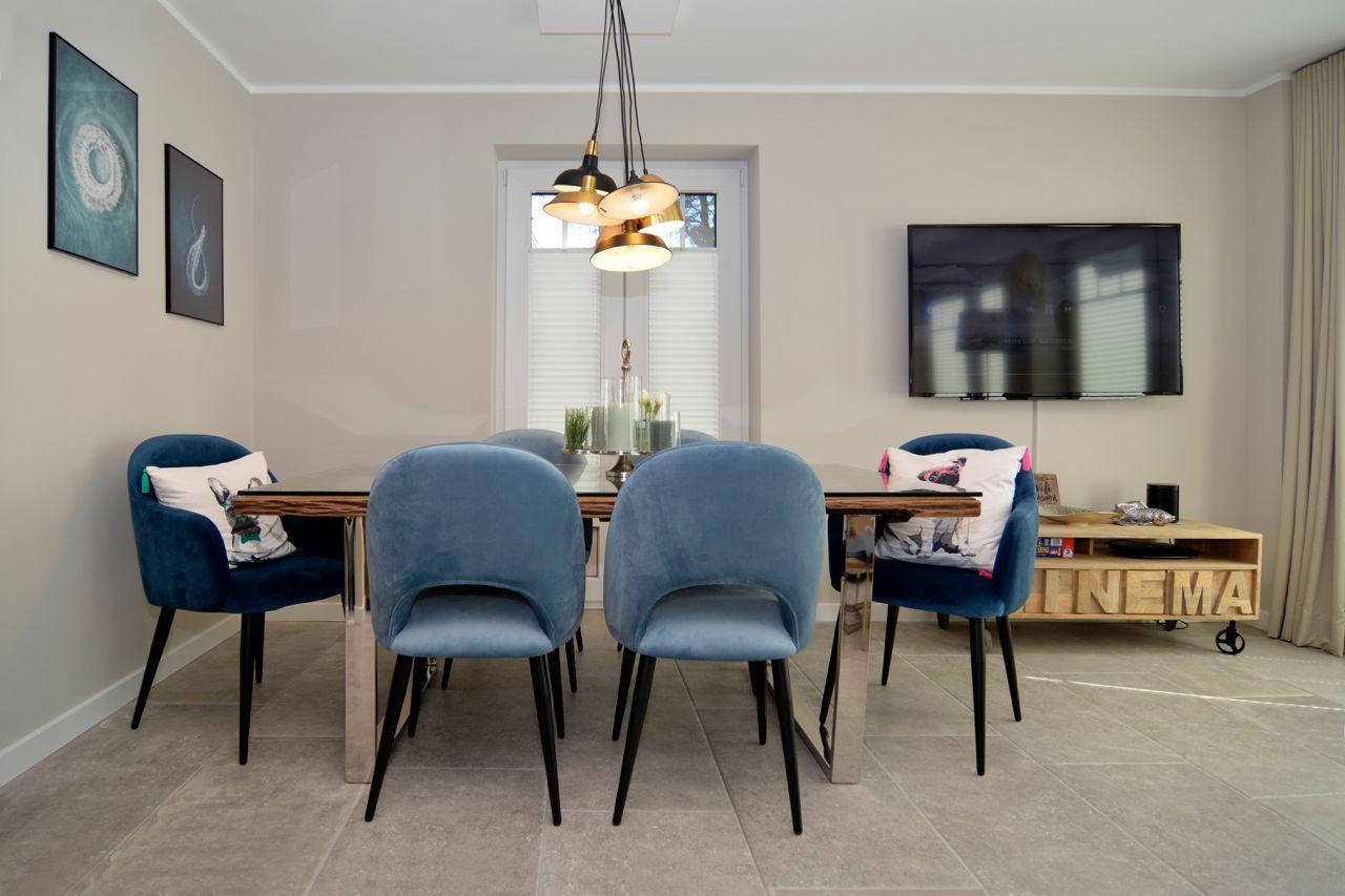 Dining area with blue chairs and TV wall.