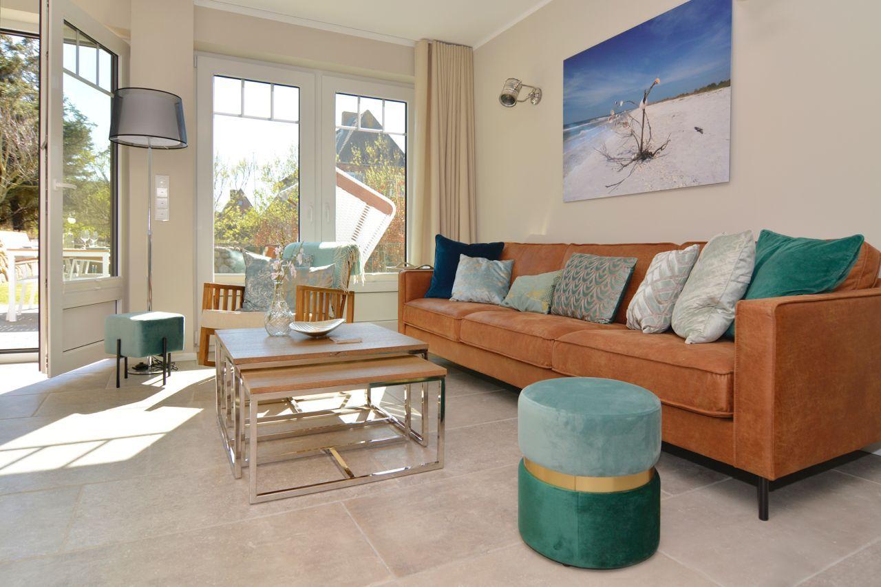 A living room with a brown sofa, green cushions, and large windows.