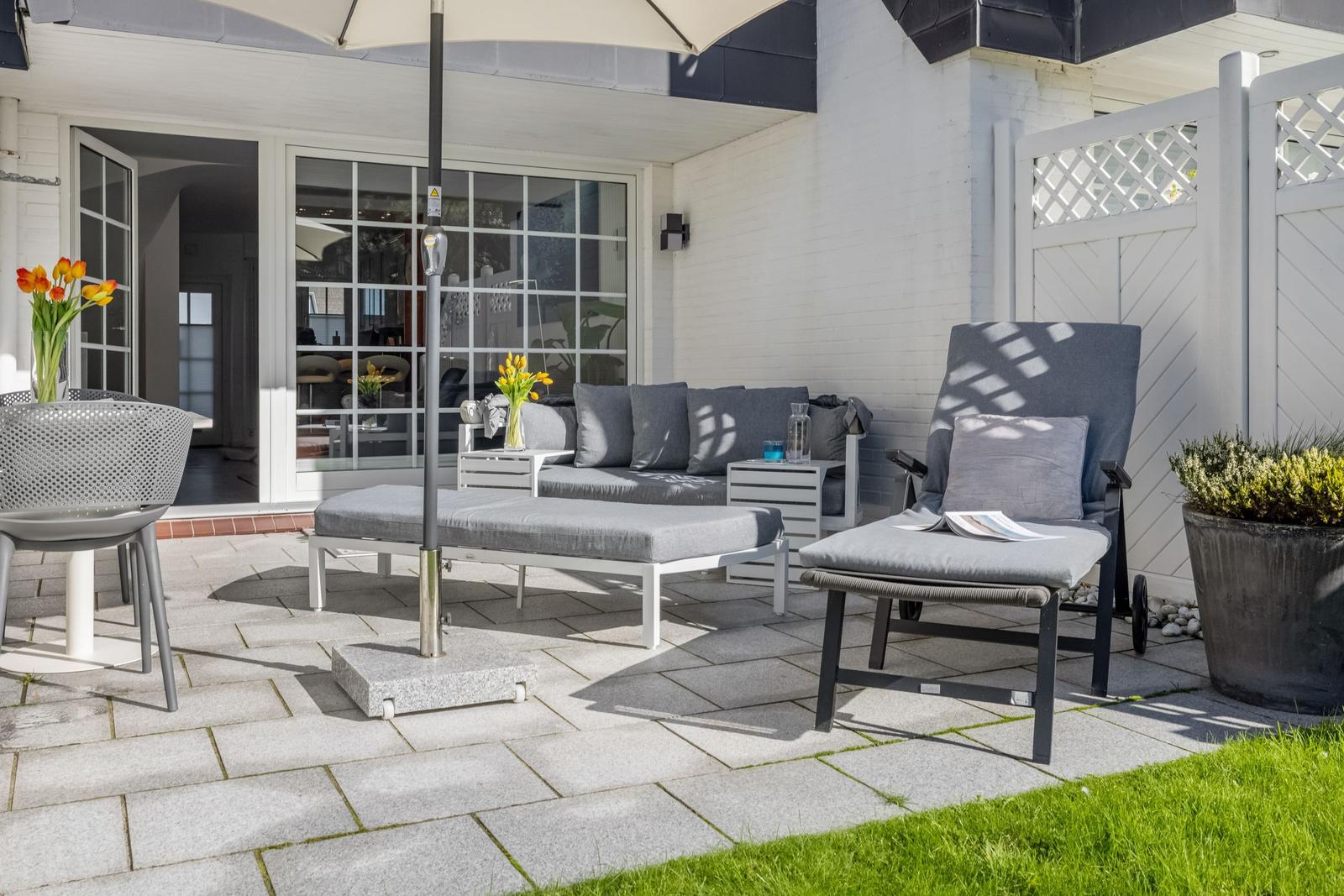 Terrace with garden furniture, parasol, and view into the house.