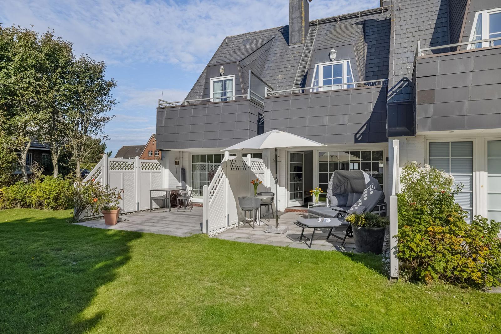 House with terrace, garden, and seating under sunshade.
