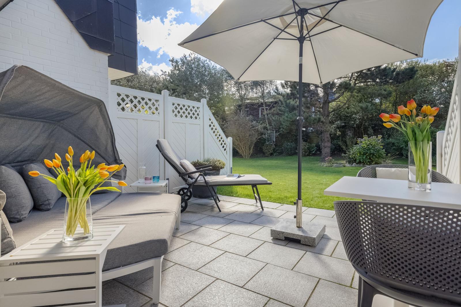 Terrace with seating, umbrella, and flower arrangements.