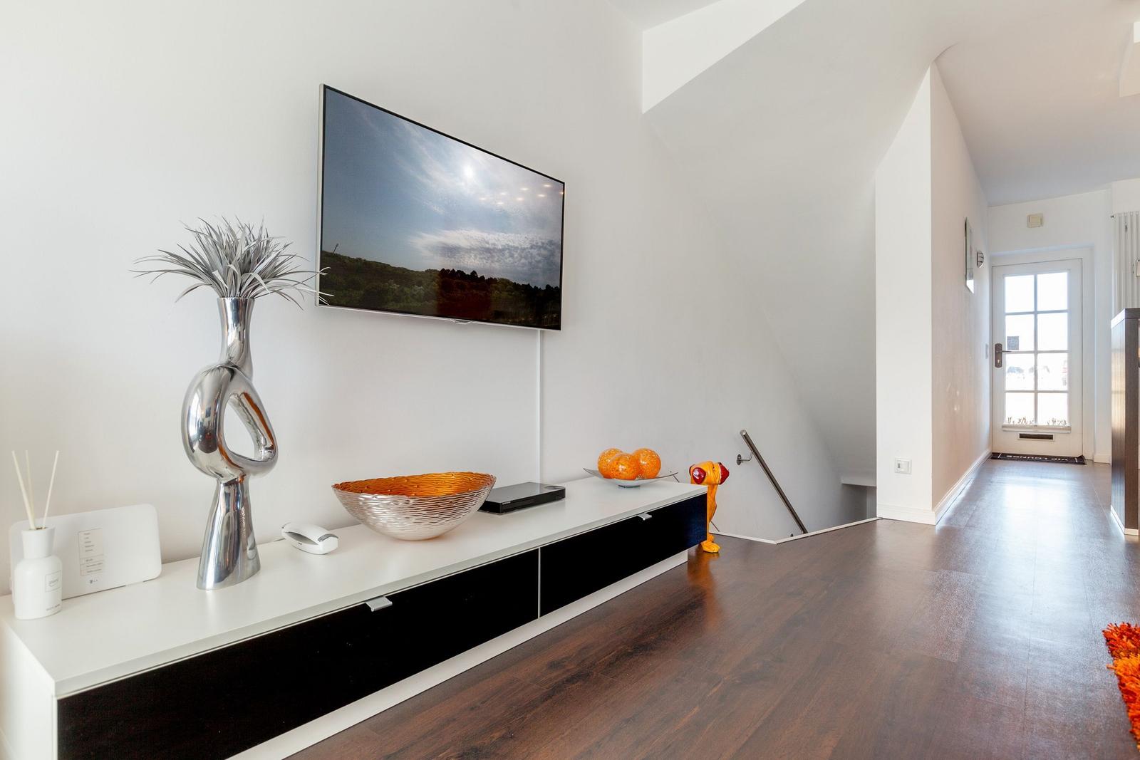 TV mounted on wall, living room with wooden floor and modern furniture
