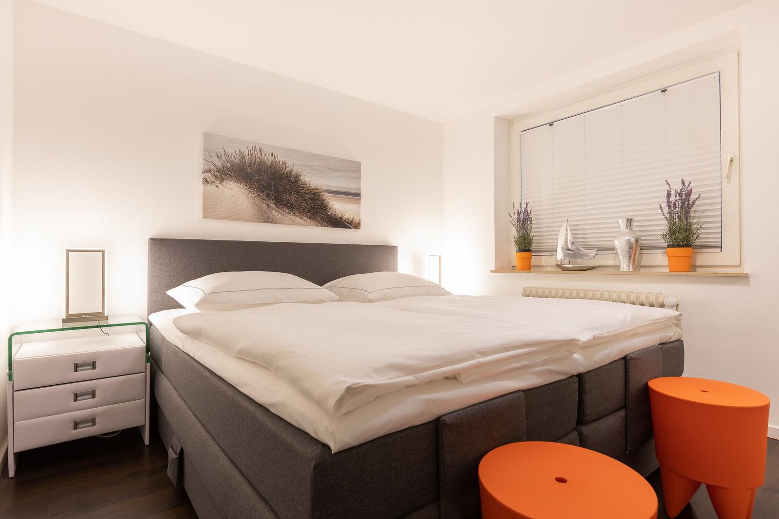 Bedroom with double bed, nightstand, and window with blinds.