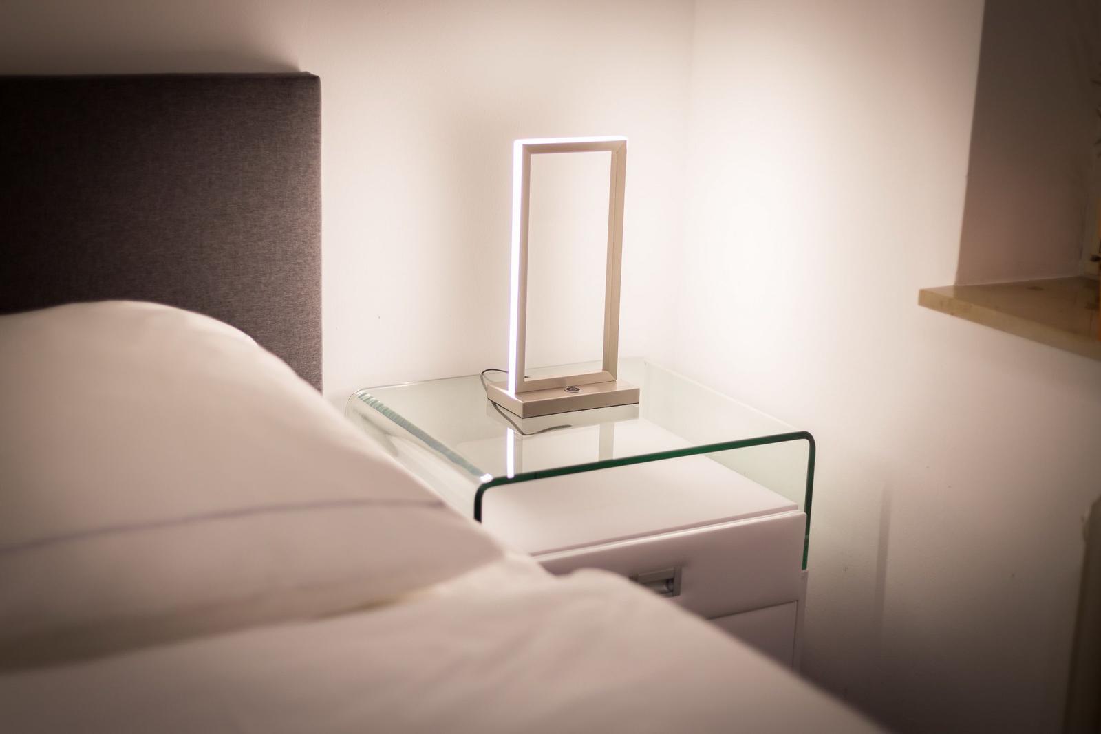 Bedroom with bed, nightstand, and modern lamp.