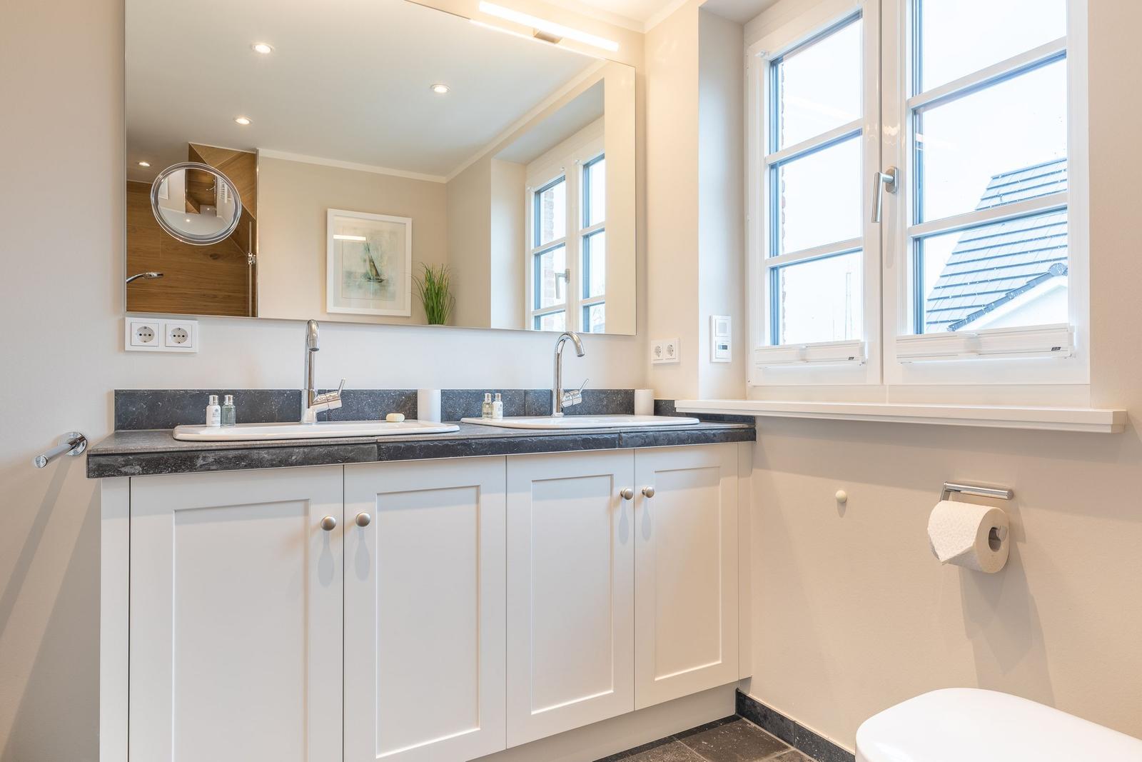 Bathroom with two sinks, mirror cabinet, and window