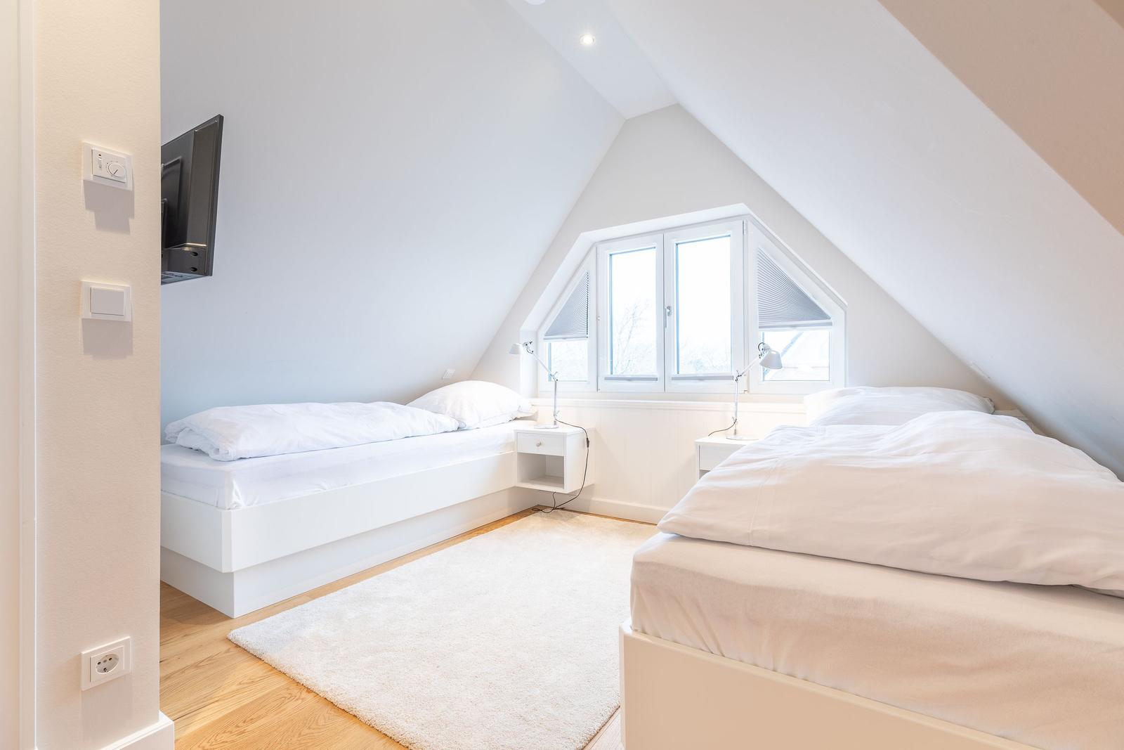 Room with two beds, window, and TV on the wall.