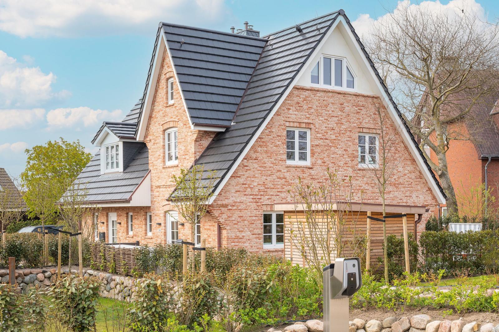 Two-story brick house with dormers and wooden garage.