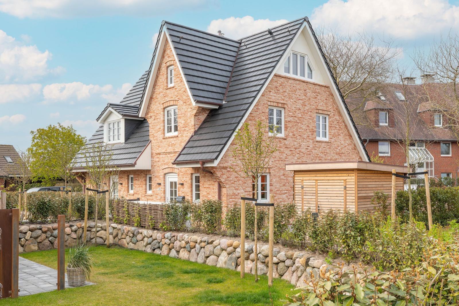 Two-story brick house with dark roof and landscaped garden