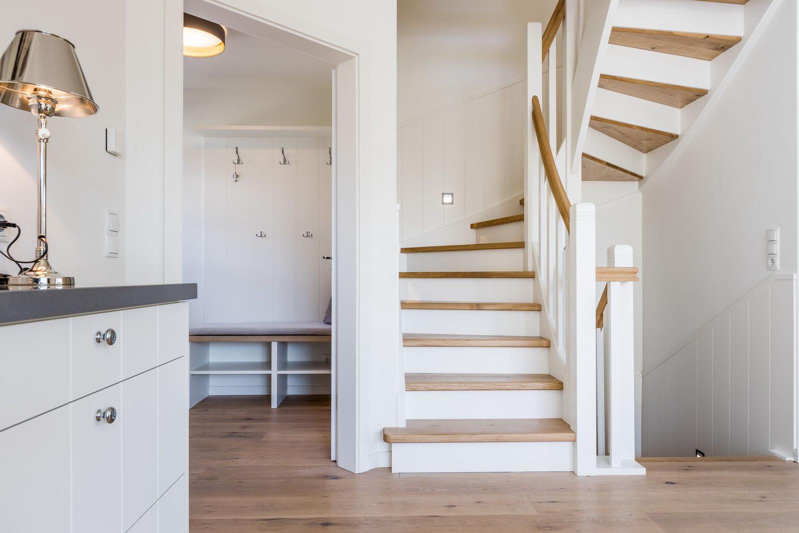 Haus mit Holztreppe, Garderobe und Schrank. Holzboden und weiße Wände.