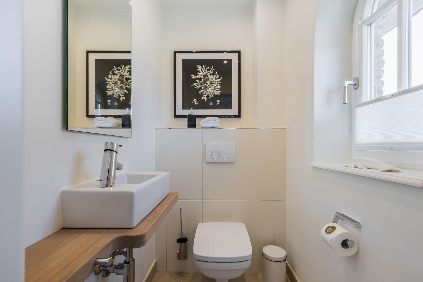 Badezimmer mit Waschbecken, Toilette und Fenster.