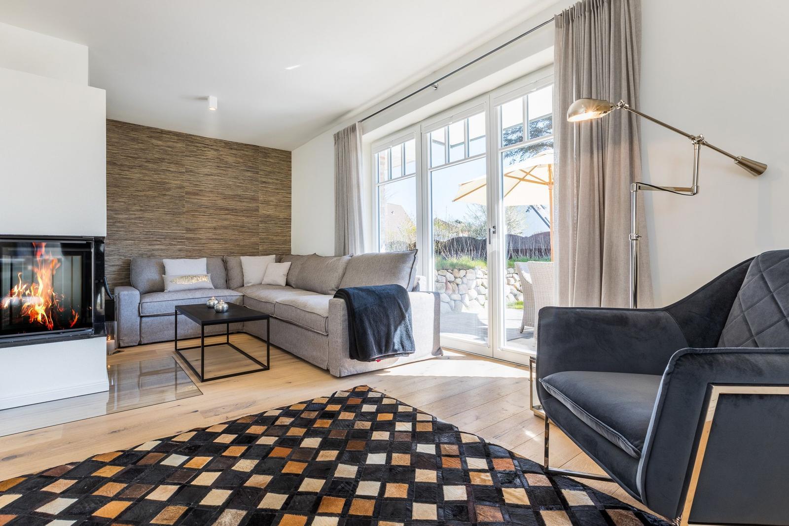 Wohnzimmer mit Sofa, Kamin und Terrasse