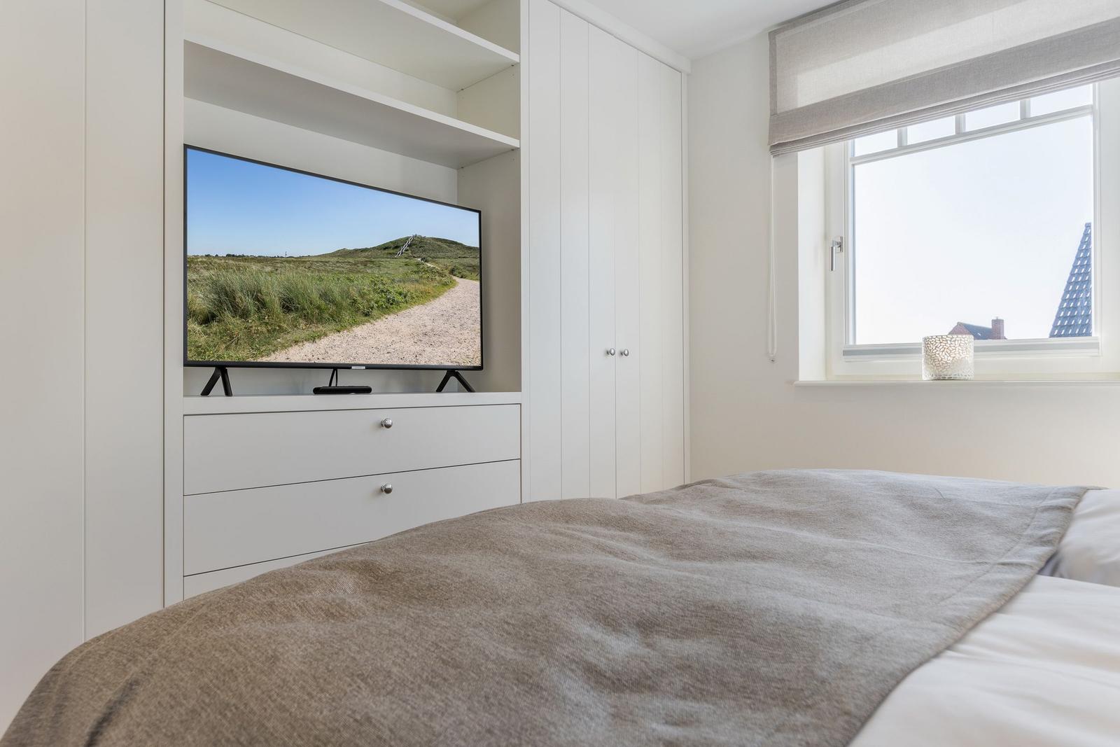 Schlafzimmer mit Bett, Fernseher und Fenster
