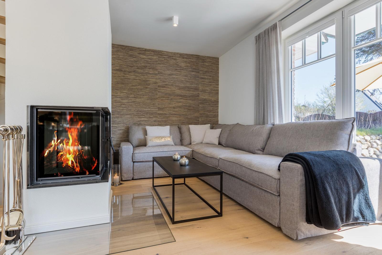 Wohnzimmer mit Sofa, Kamin und großem Fenster