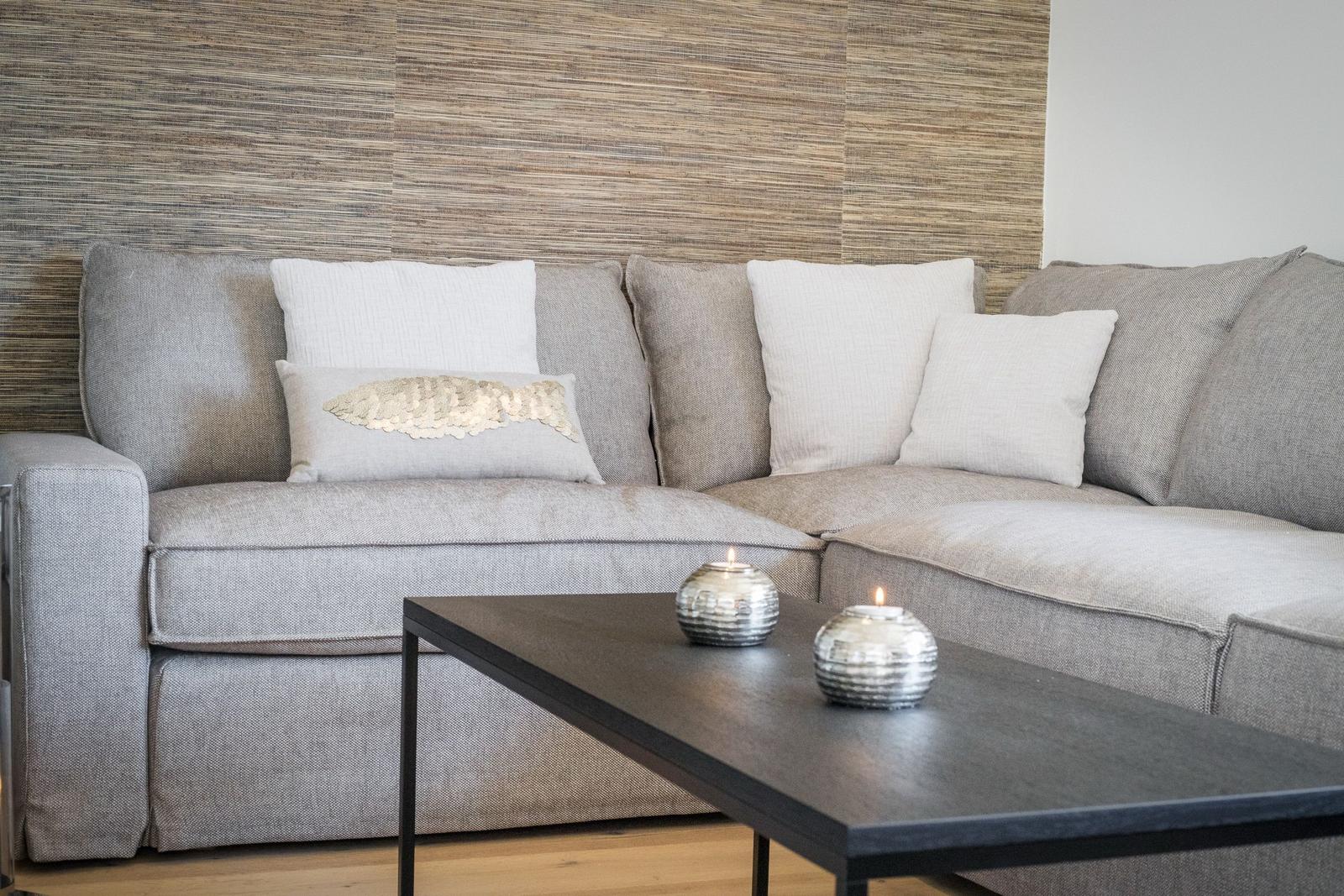 Grauer Sofa mit Kissen und Tisch mit Kerzen.