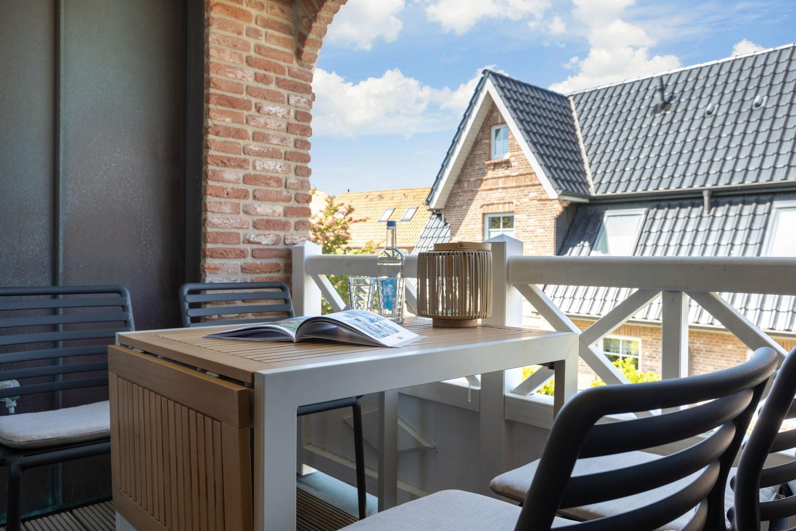 Terrace with table, chairs, and view of rooftops.