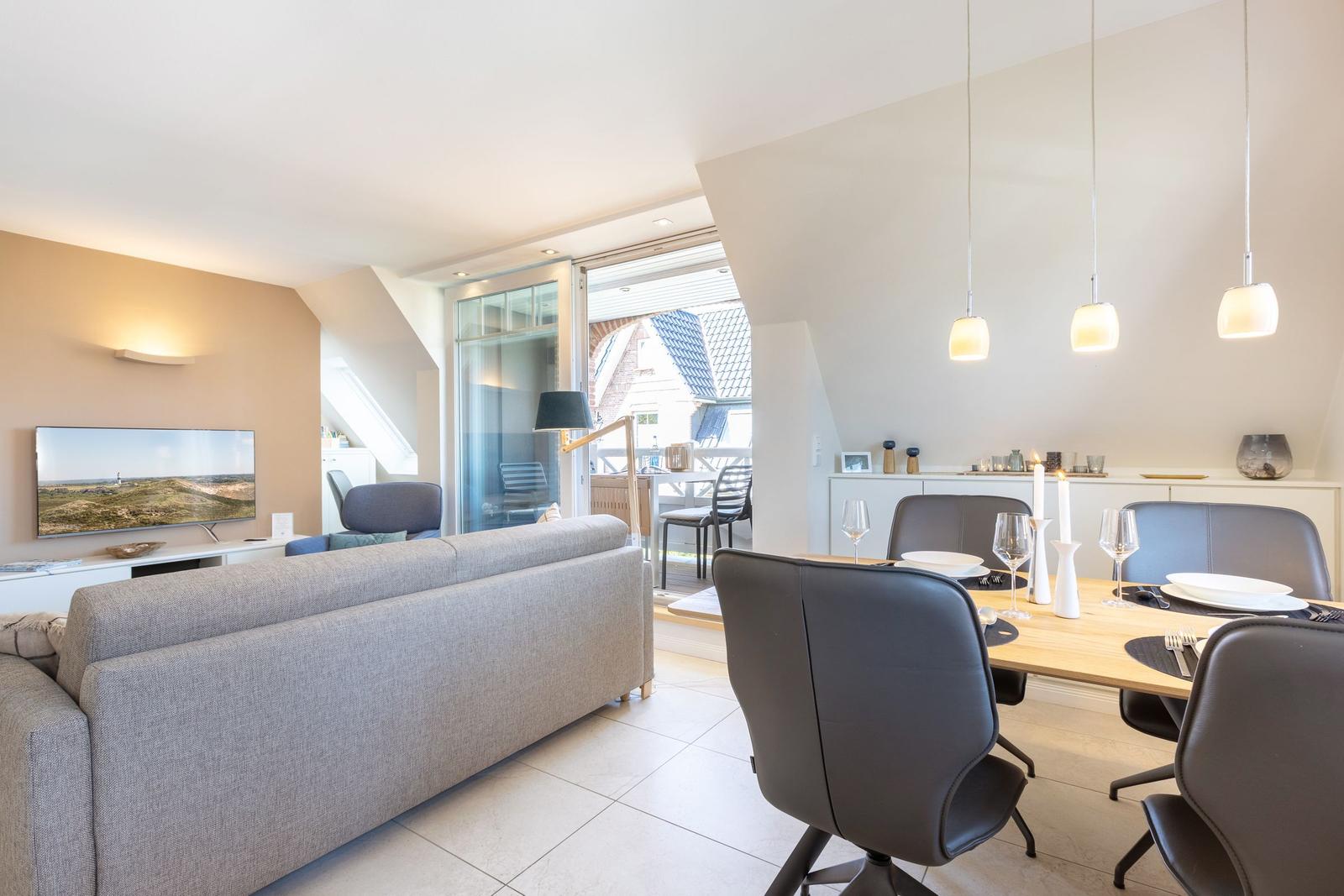 Living and dining area with sofa, TV, and table with chairs.