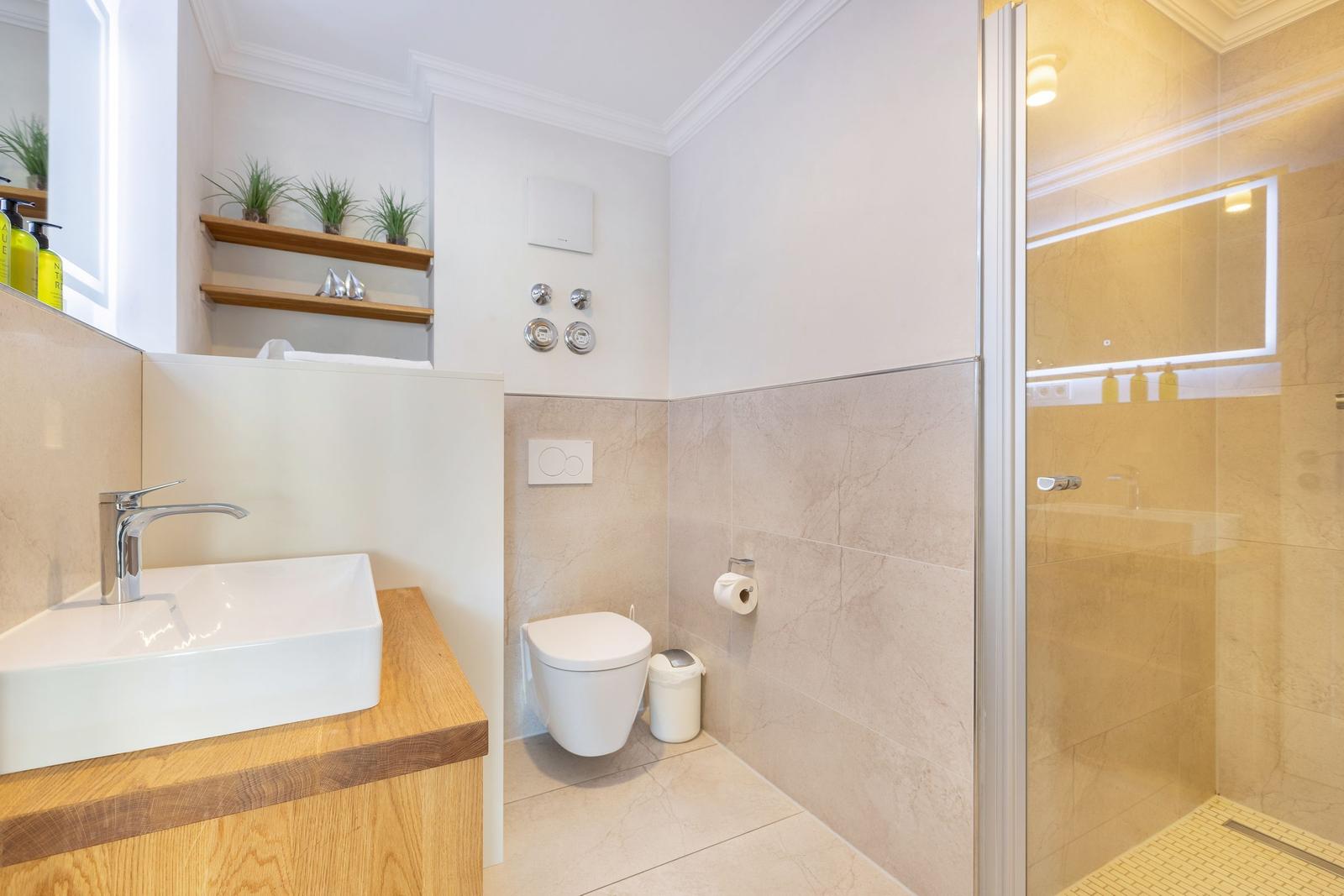 Bathroom with shower, toilet, and sink on wooden base.