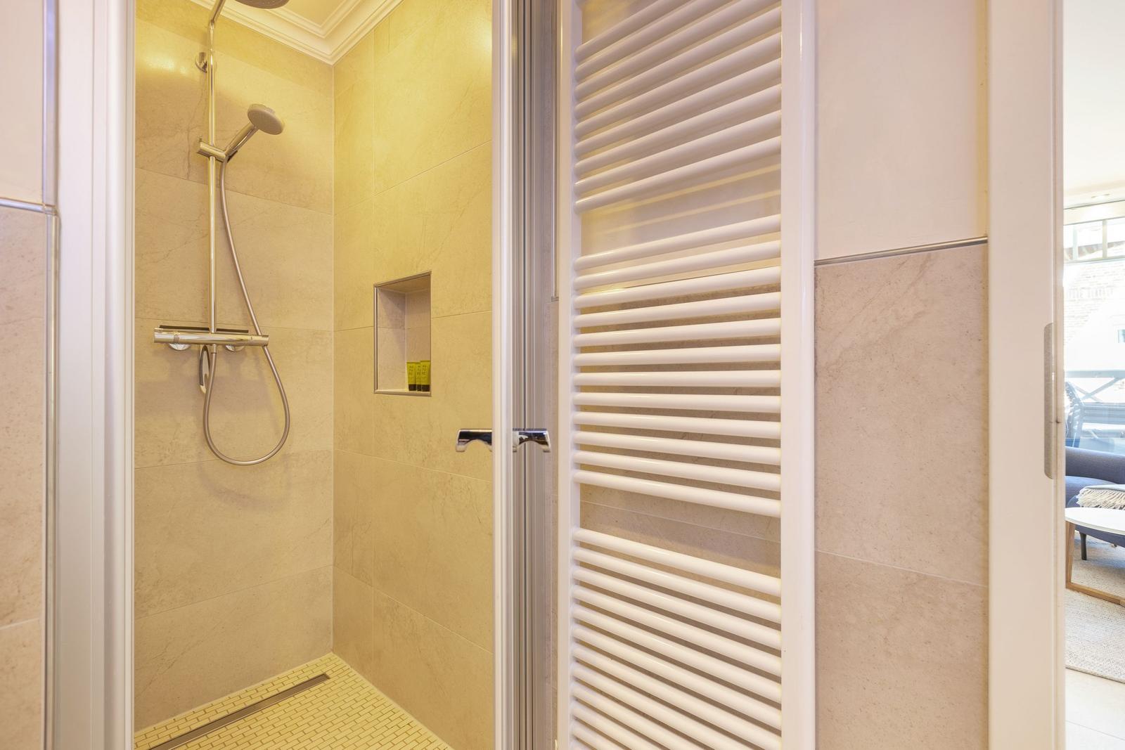 Shower with showerhead, built-in shelf, and heater.