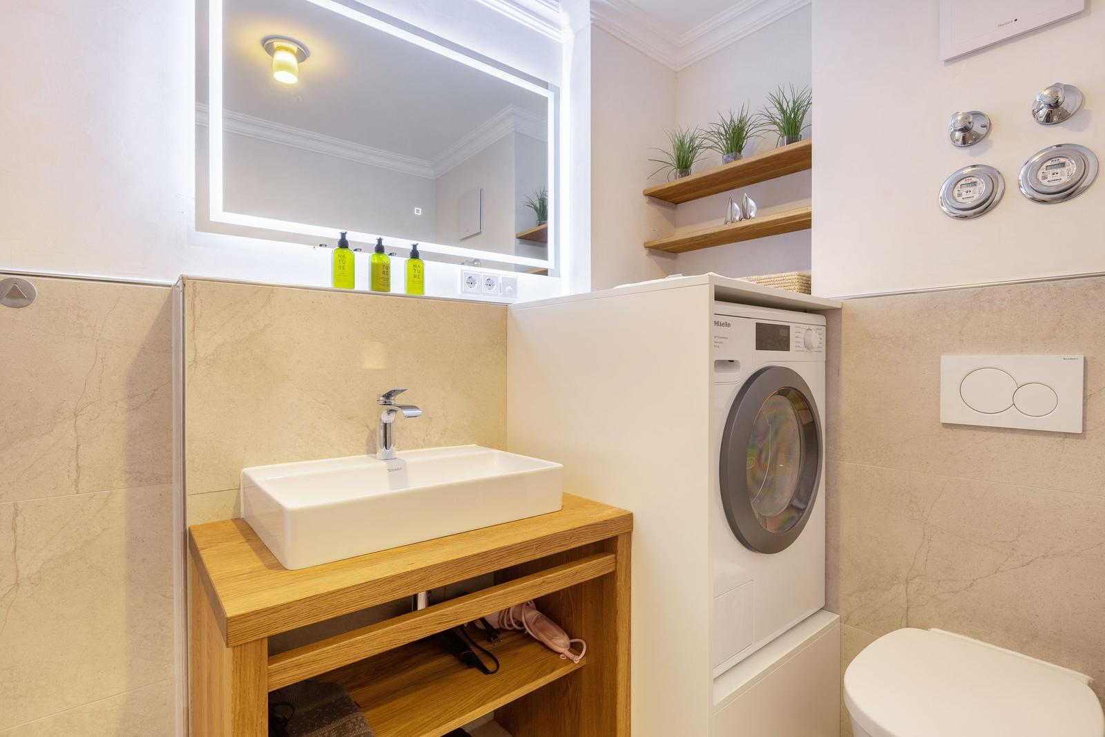 Bathroom with washing machine, sink, and mirror