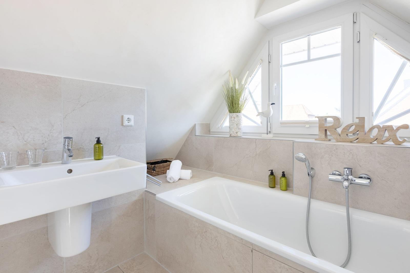 Bathroom with bathtub, sink, and window