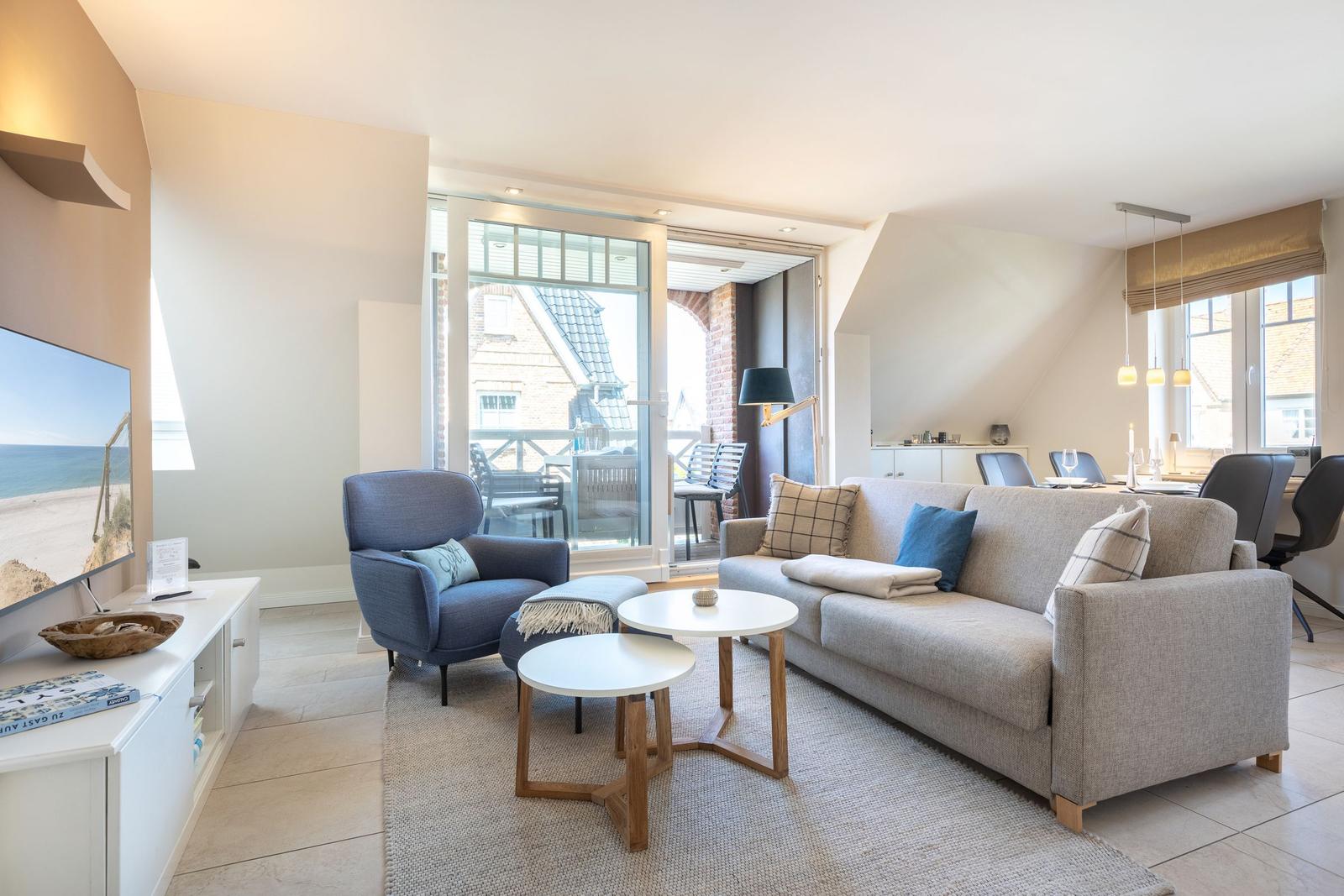 Living and dining area with sofa, armchair, and TV. Terrace with view of house.