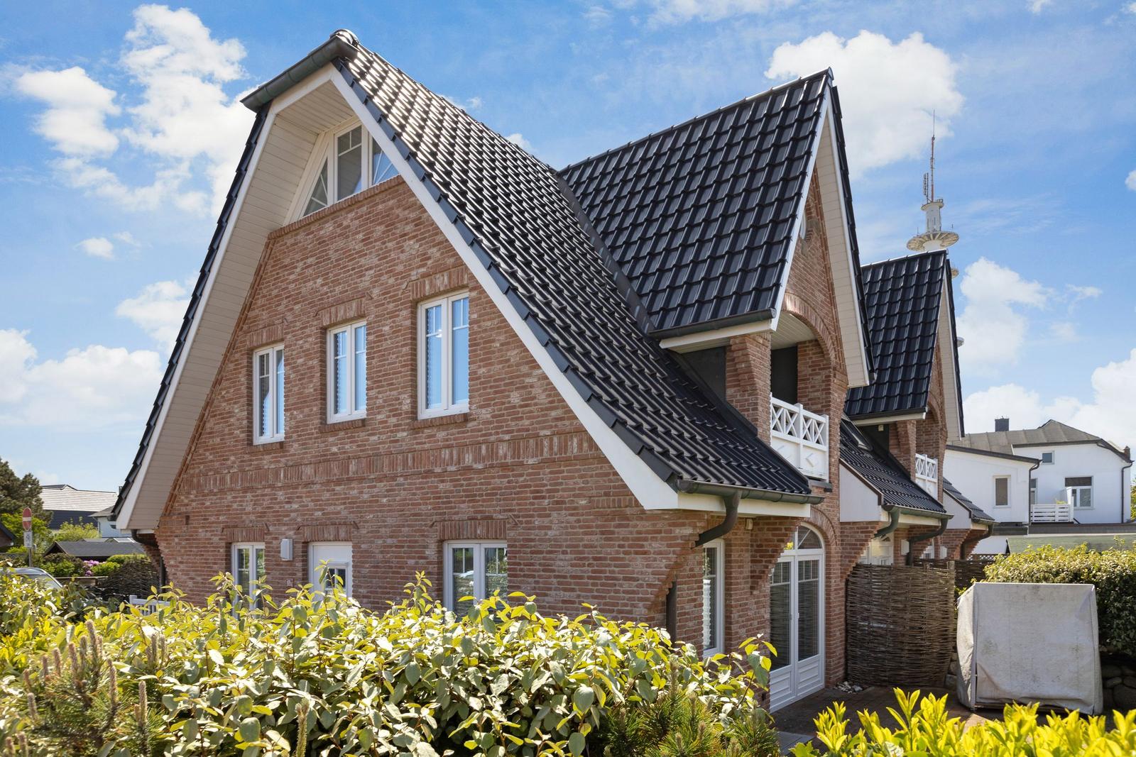 Two-story brick building with black gabled roof and white windows.