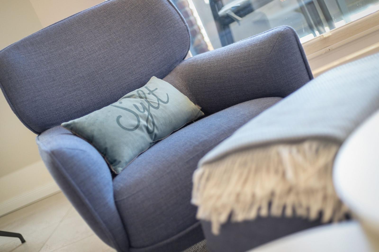 A blue armchair with cushion and blanket