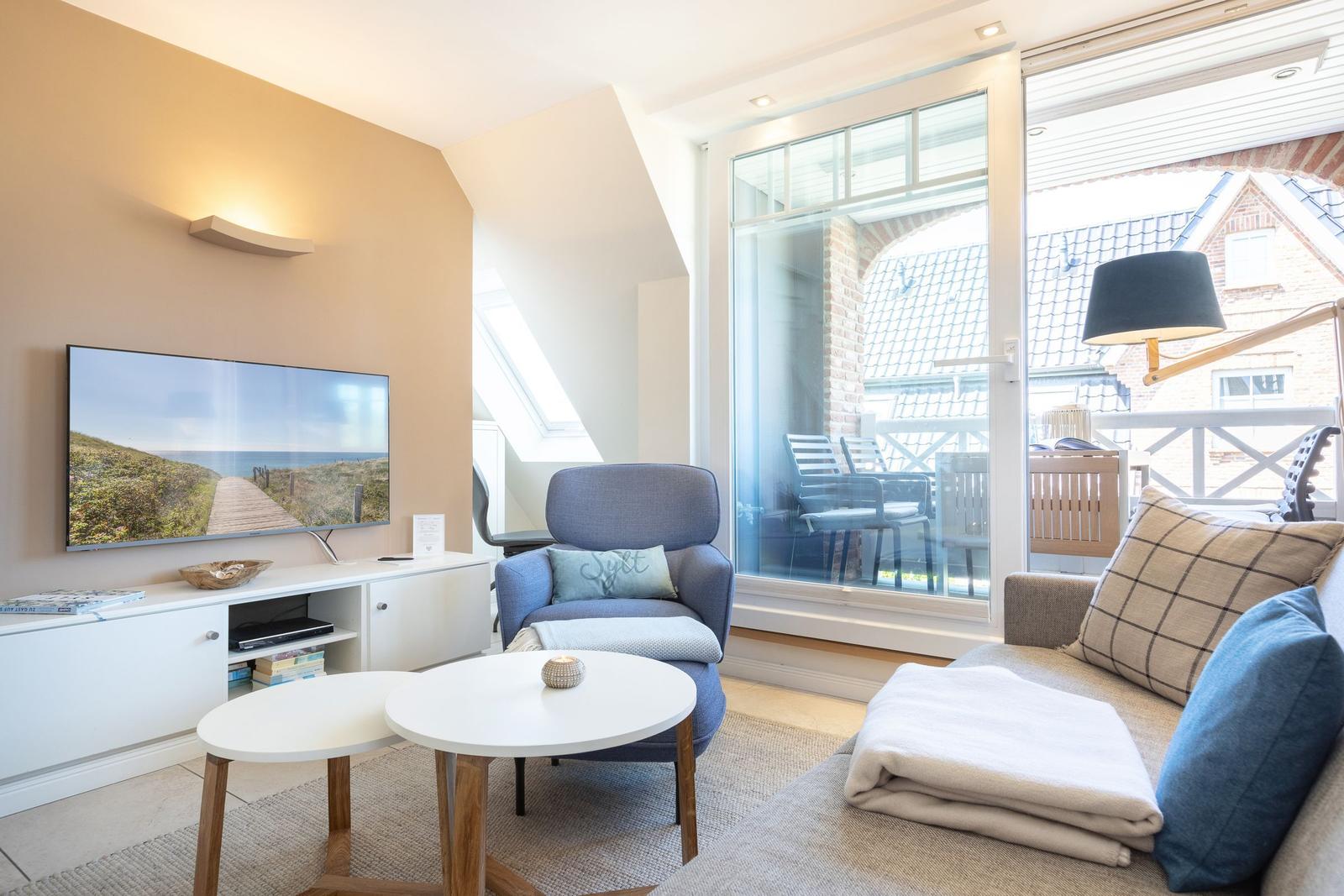 Living room with TV, seating, and view to balcony.