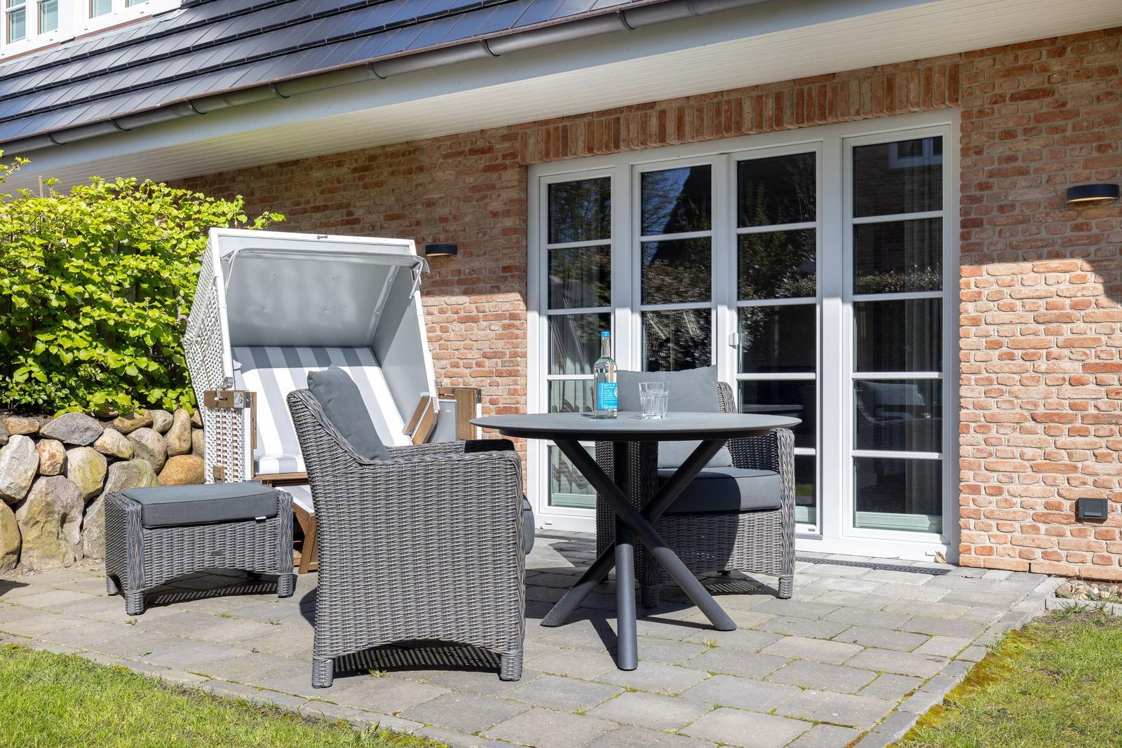Terrasse mit Liegestuhl, Tisch und Stühlen vor Backsteinhaus