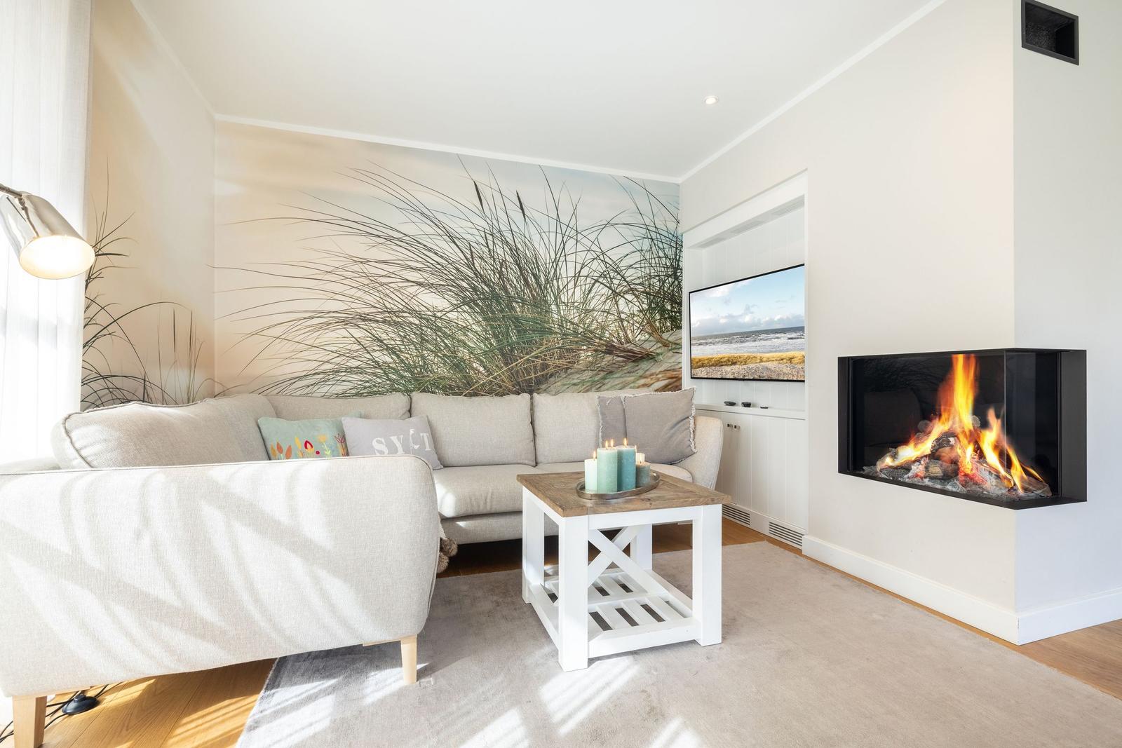 Wohnzimmer mit Sofa, Kamin und Wandbild von Strandgras.